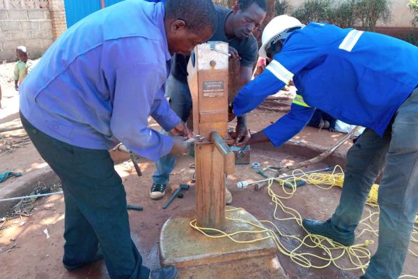 Ein Brunnen in Mosambik wird von drei Männern aufgebaut