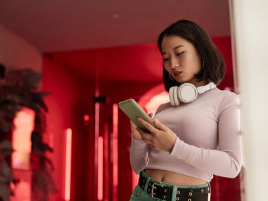 Porträt einer jungen Frau, die in einem futuristischen roten Büro ein Smartphone benutzt