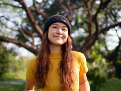 Eine Frau mit Mütze steht in einem Park.