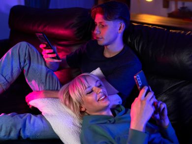 Ein Pärchen liegt auf dem Sofa und beide sind am Handy beschäftigt