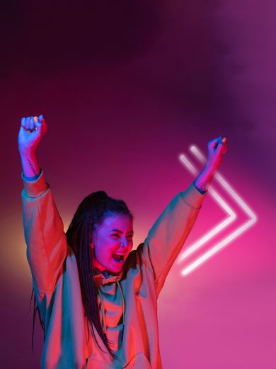 Eine jubelnde Frau hebt die Hände in die Luft und freut sich.