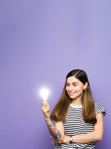 Eine lächelnde Frau hält eine leuchtende Glühbirne in der Hand