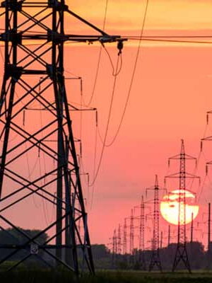 Eine Reihe von Strommaste vor einem Sonnenuntergang.