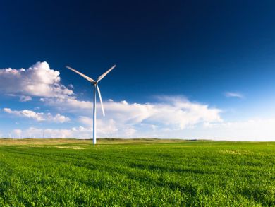 Windkraftanlage Eine Windkraftanlage auf einer grünen Wiese vor blauem Himmel