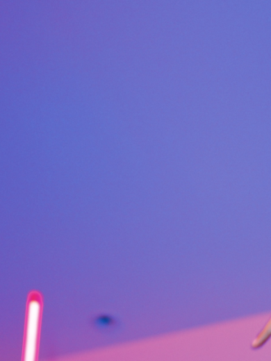 Tanzende Frau mit lockigen Haaren vor Neonlichtern