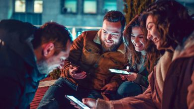 Vier lächelnde Freundinnen und Freunde mit Smartphones in der Hand