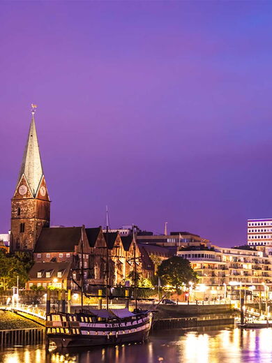 Das erleuchtete Ufer von Bremen mit einer Kirche und einer Brücke