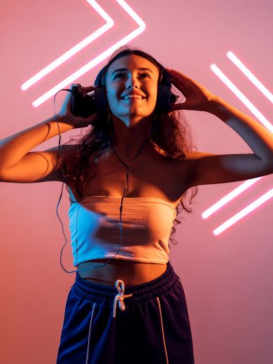 Eine Frau mit Kopfhörern hält ihr Handy in der Hand und steht vor zwei Pfeilen, die nach rechts zeigen.