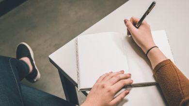 Ein Notizbuch liegt auf dem Tisch mit zwei Händen