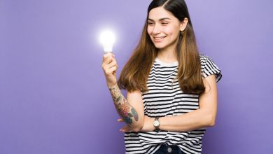 Eine lächelnde Frau hält eine leuchtende Glühbirne in der Hand