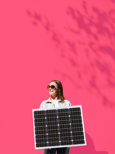 Eine Frau hält ein Photovoltaik Panel vor einem rosa Hintergrund