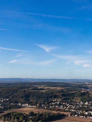 Eine Landschaft mit Fluss, Häusern und Wäldern mit blauem Himmel.