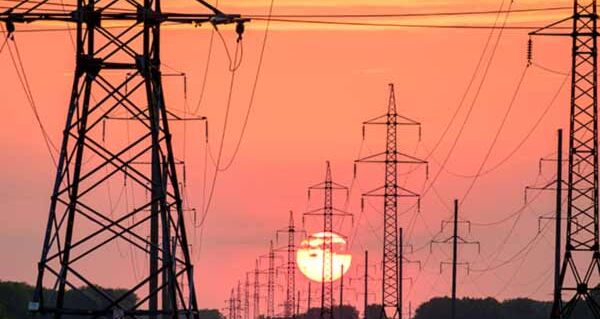 Eine Reihe von Strommaste vor einem Sonnenuntergang.