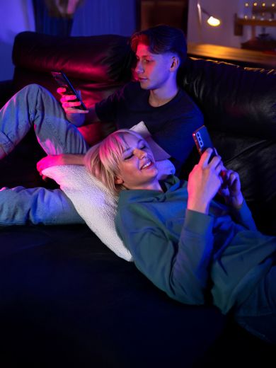 Ein Pärchen liegt auf dem Sofa und beide sind am Handy beschäftigt